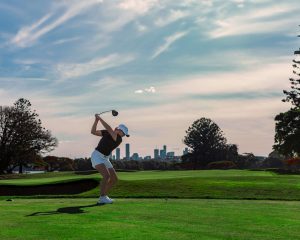 woman golfing with skyline